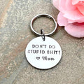 Round Don't Do Stupid Shit keyring hand stamped with a heart and Mum signature, beside a pink flower
