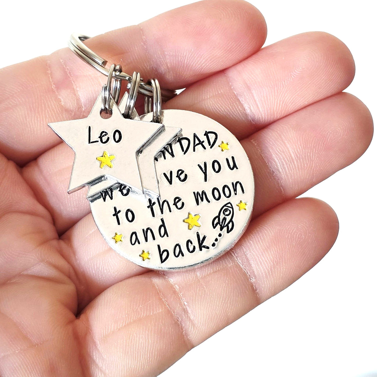 Grandad We Love You to the Moon and Back keyring with a Leo star name tag, held in a hand
