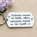Distance means so little when someone means so much keyring with outline hearts and arrow details, beside lilac flowers
