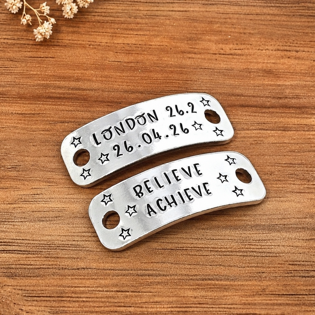 Personalised running shoe tags stamped with London 26.2 race details and Believe Achieve, decorated with stars and displayed on wood


