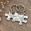 Personalised stainless steel puzzle keyring set engraved with 27th October 2026, individual initials and outline hearts on rustic wood
