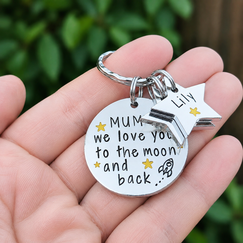 Mummy moon and back keyring held in a hand, showing personalised star tags and yellow star details.