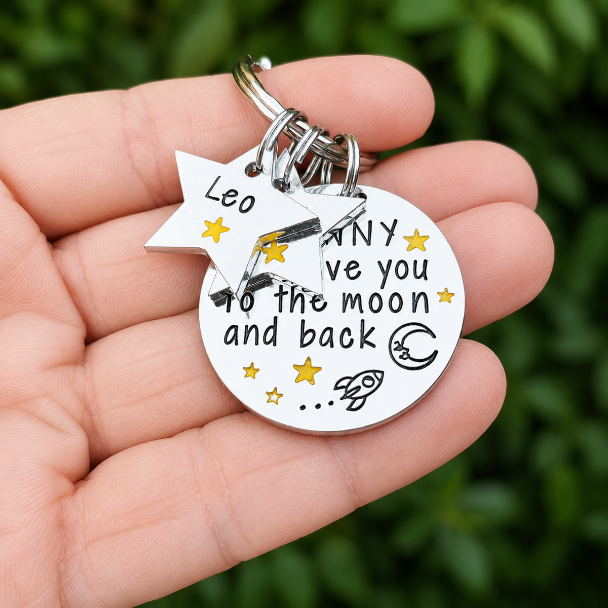 Personalised Nanny moon and back keyring held in a hand, with star name tags and a moon, rocket and gold-coloured star design