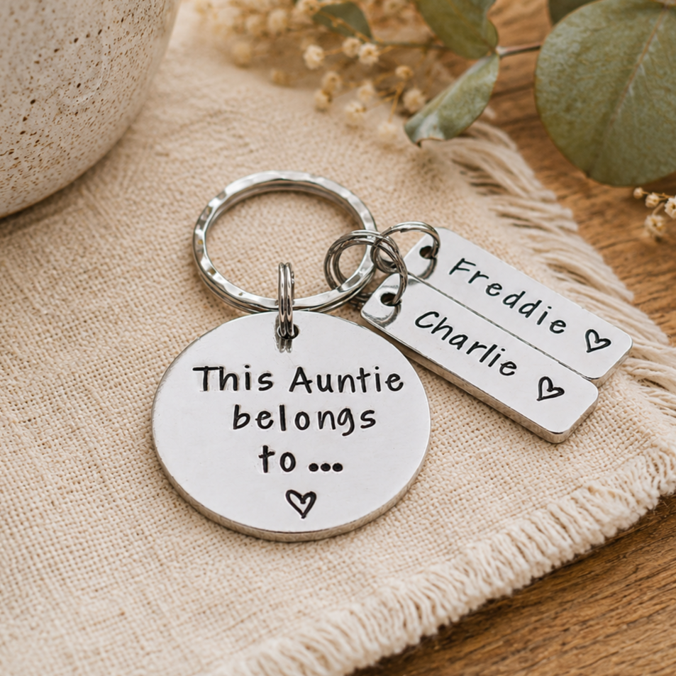 A silver-tone metal keychain set with a round disc charm and two rectangular tags, engraved with the names Freddie and Charlie and the phrase 'This Auntie belongs to.