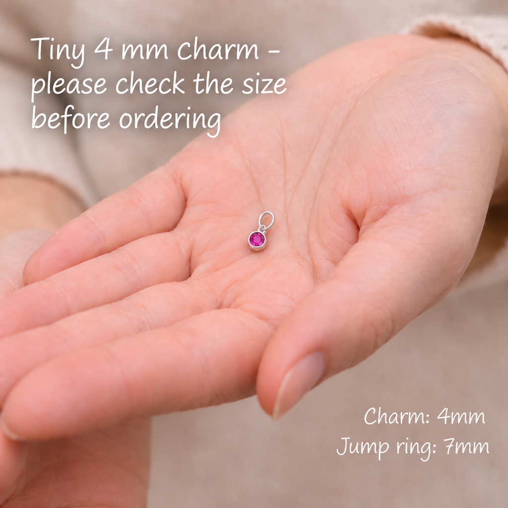 Tiny pink birthstone charm shown in a palm, with 4 mm charm and 7 mm ring measurements