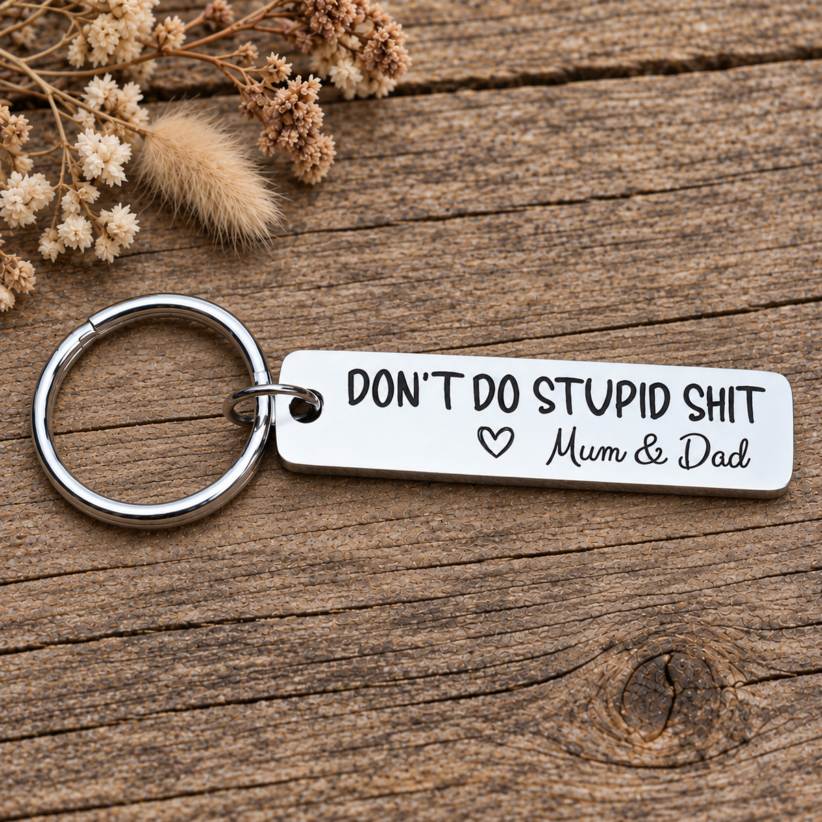 Rectangular stainless steel Don't Do Stupid Shit keyring with Mum & Dad signature and heart on a wooden background
