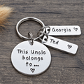 A silver metal keychain with a round disc charm and two rectangular tags, one stamped with 'Georgia' and the other with 'Ted', plus the main tag reading 'This Uncle belongs to.