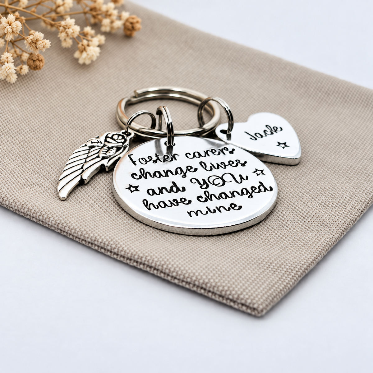 Angled view of a foster carer thank you keyring with a heart name tag and decorative wing charm