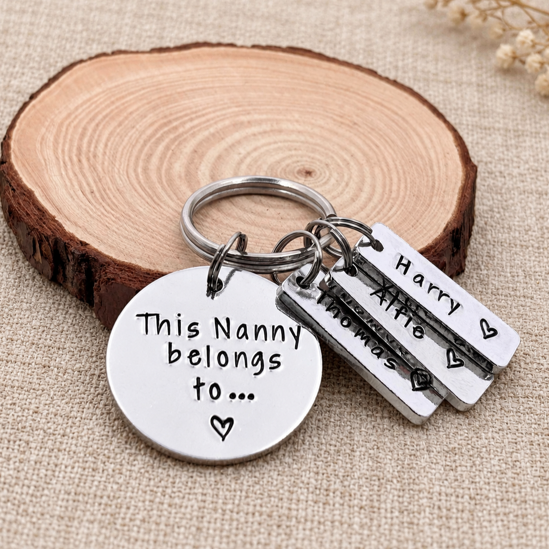 A silver-toned metal keychain with a round engraved disc reading 'This Nanny belongs to.