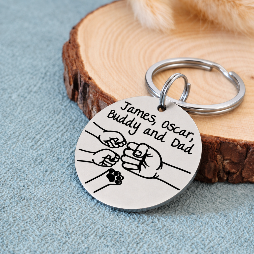 Angled view of a personalised family fist bump keyring with a pet paw on blue fabric beside a wood slice
