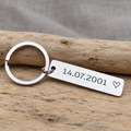 Personalised stainless steel date keyring engraved with 14.07.2001 and an outline heart on rustic wood
