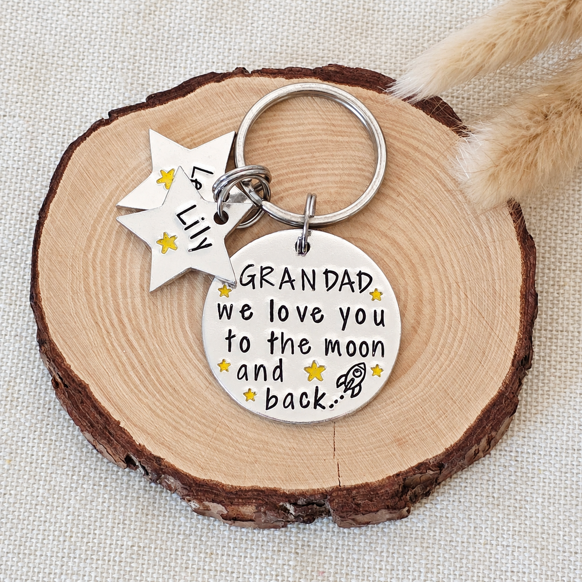 Hand stamped Grandad Moon and Back keyring with personalised star tags displayed on a wood slice
