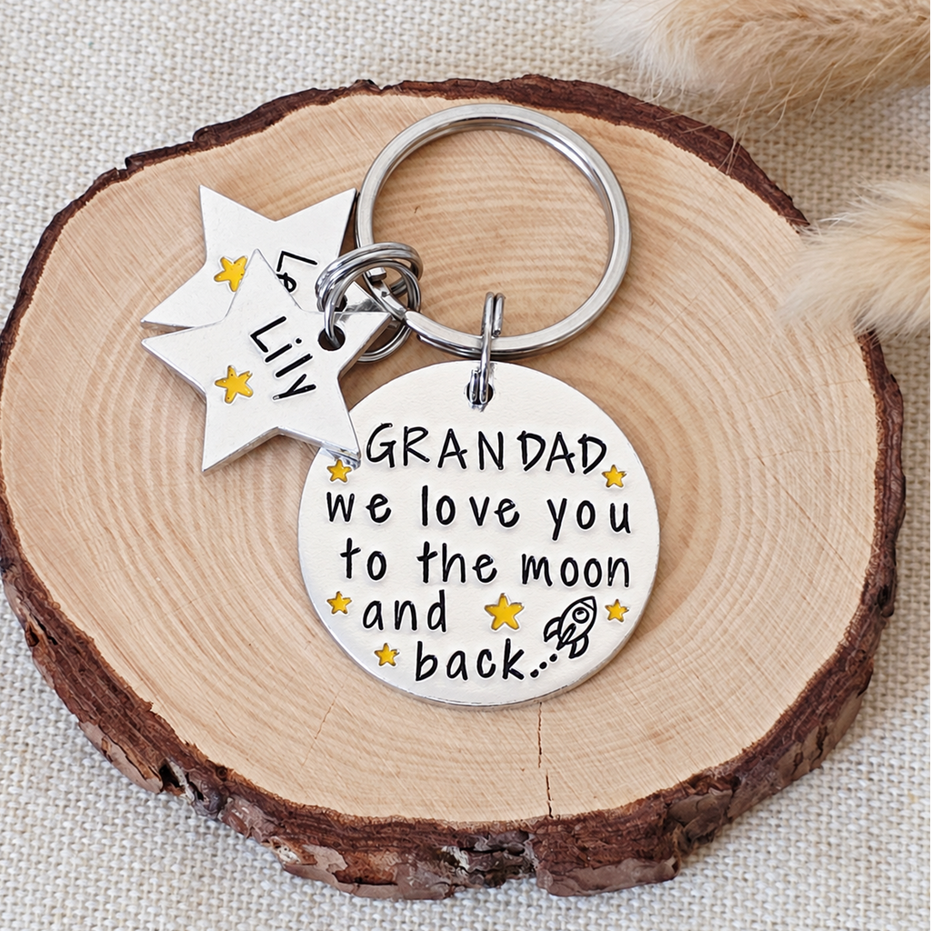 Personalised Grandad Moon and Back keyring with yellow stars, a rocket and star-shaped name tags on a wood slice
