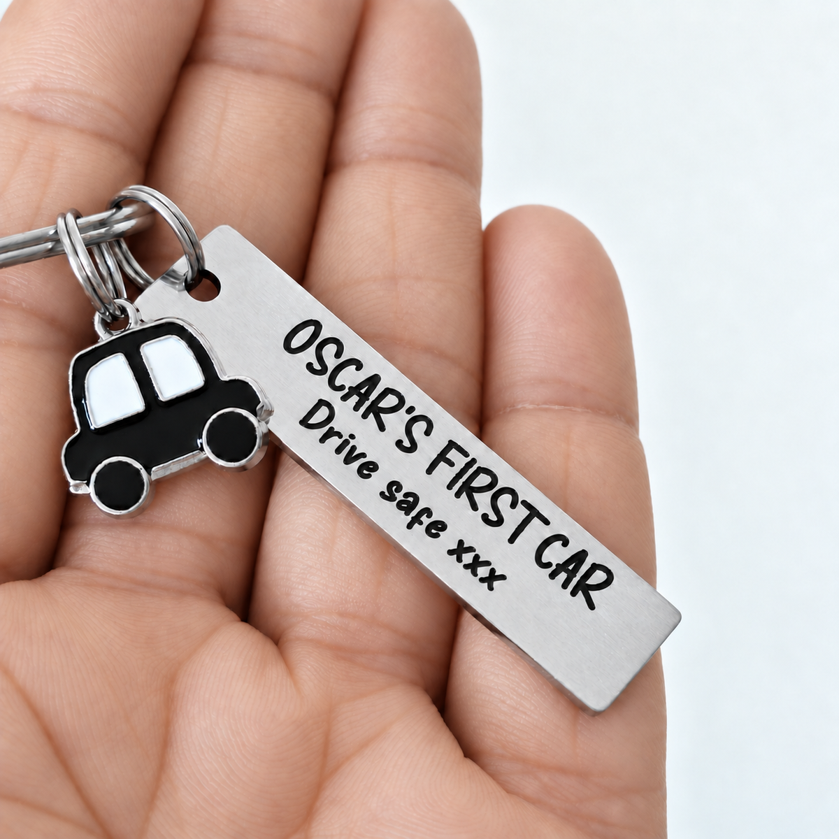 Hand holding personalised first car keyring with black car charm