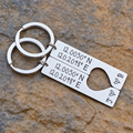 Matching stainless steel coordinates keyrings with a shared heart cut-out, engraved initials J and B and small hearts, displayed on stone
