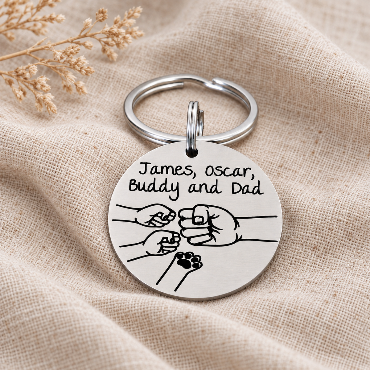 Personalised Dad fist bump keyring engraved with James, Oscar, Buddy and Dad, featuring two small fists and a pet paw on natural linen
