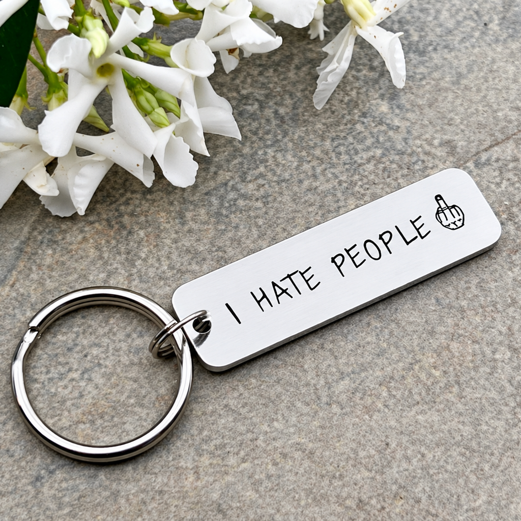 Close-up of an aluminium I Hate People keyring showing the stamped lettering and middle finger symbol
