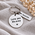 Close-up of a Love you Mummy keyring with a round message tag and a rectangular Jessica name tag on linen fabric